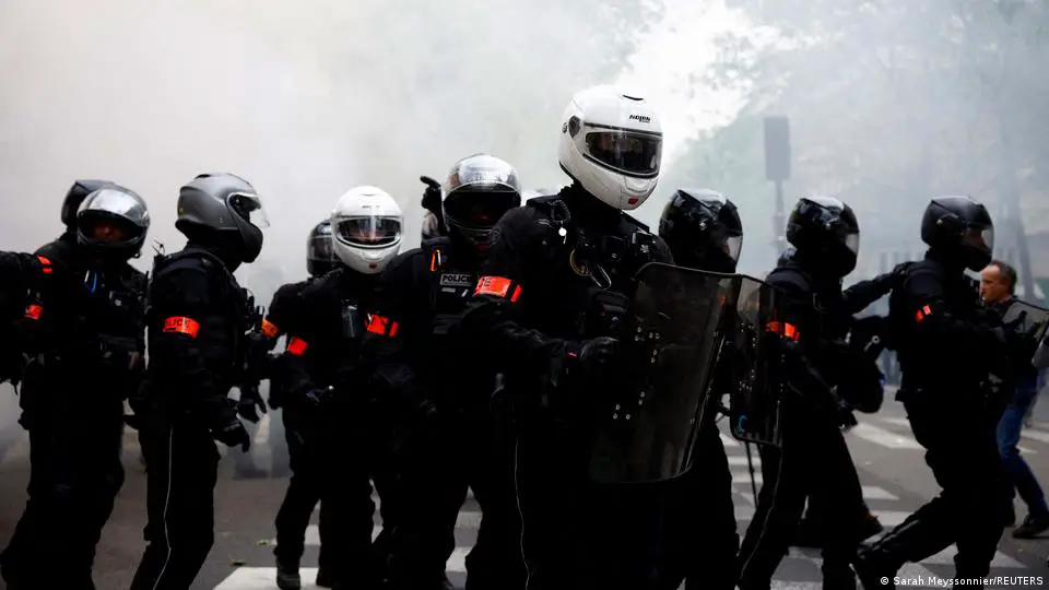 Mitglieder der motorisierten, gewalttätigen Repressionspolizeibrigaden stehen auf Position, während Demonstranten in Paris marschieren